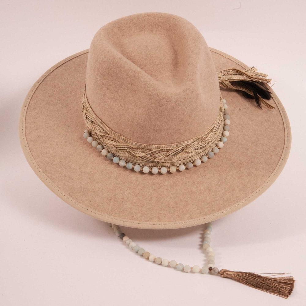 A top view of a cream cowboy hat with a beaded hat band