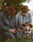 A family talking under a tree wearing brown hats